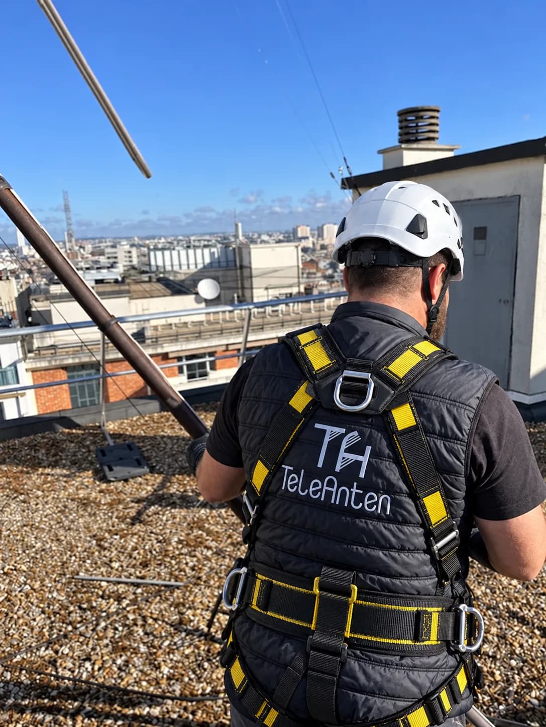 Antenniste TELEANTEN en harnais installant une antenne sur le toit d'un immeuble à Paris