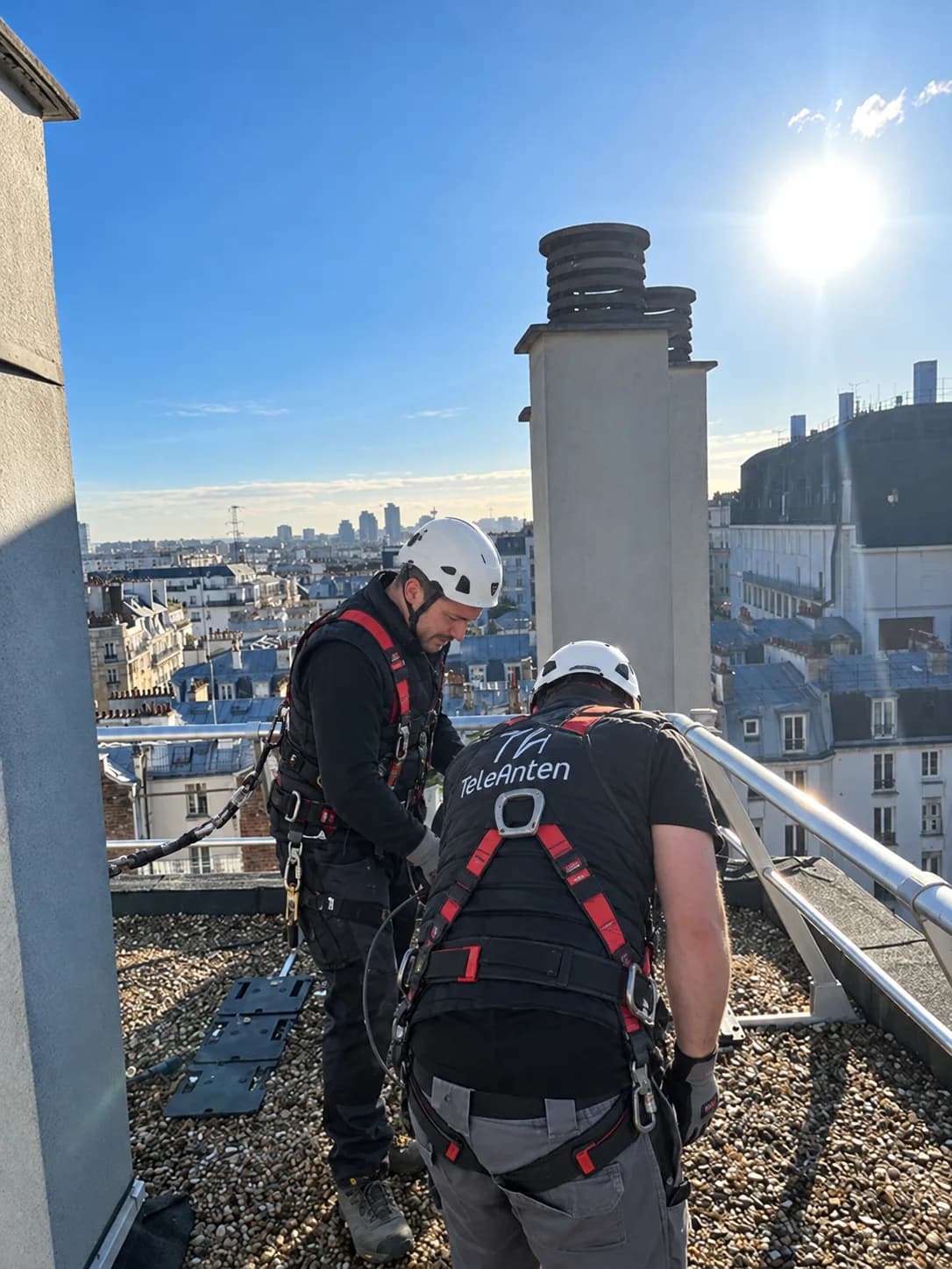 Deux antennistes TELEANTEN équipés de casques et de harnais sur un toit de Paris